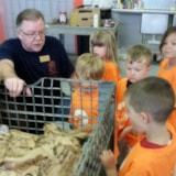 Volunteer explains food sorting to children at food bank