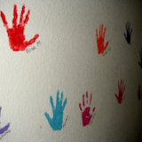 Painted handprints with names on a community wall in Honduras