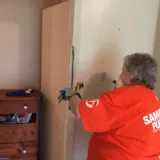 Volunteer removes water-damaged trim in Monroe flood cleanup