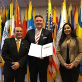 Judah 1 delegates stand with document among UN flags in New York
