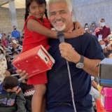 Volunteer speaks as child receives shoes at local aid event