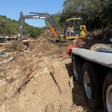Excavator clears flood debris along the Kerrville riverbank