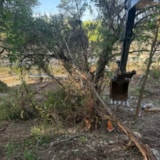 Excavator clears flood debris along a Kerrville riverbank
