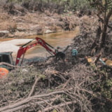 An excavator clears flood debris in a Kerrville, Texas creek bed