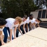 Volunteers lift plywood panels for community rebuilding
