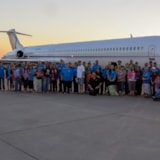 Mission team gathers by an aircraft for missionary support