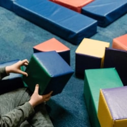Volunteer engages a child with soft blocks at Champions Club