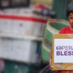 Child holds an Operation Blessing relief box in the community